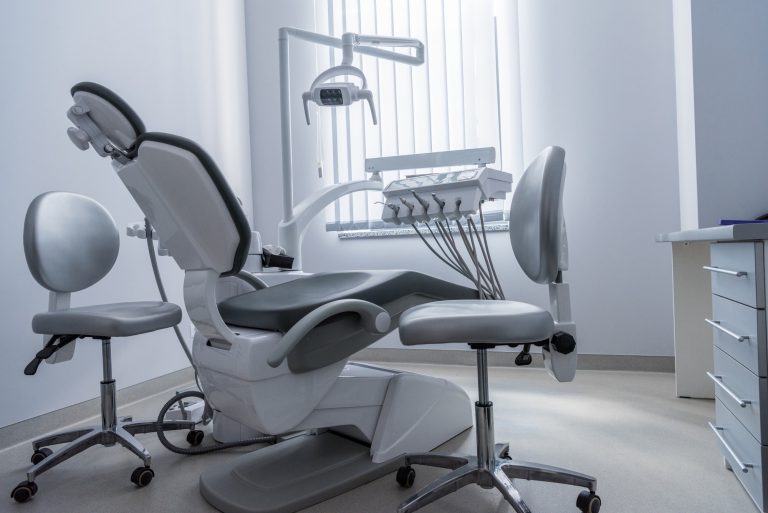 empty dentist office with chair and various dental equipment